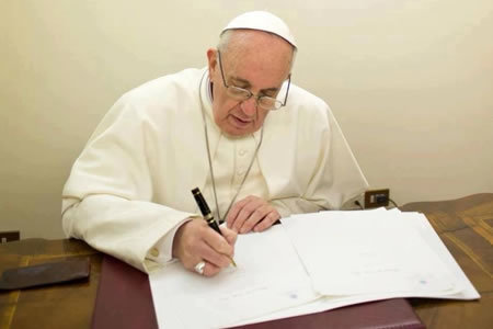 El Papa Francisco escribiendo.